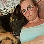 woman, dog, german_shepherd, glasses, couch, floral_pattern, tattoo, bracelet, relaxing, indoor, close_up, affection, pet, companion, portrait, casual_clothing, resting, human_animal_bond, head, face
