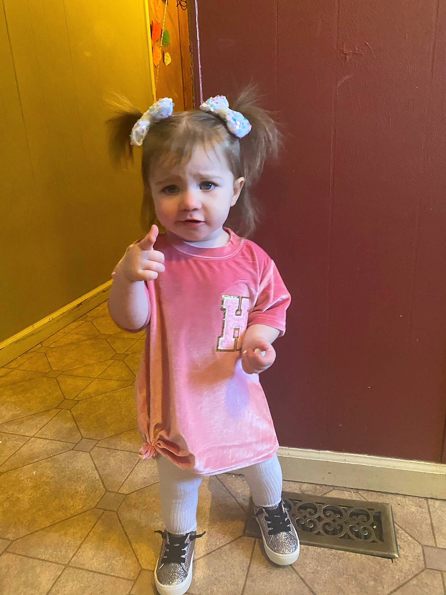 Hattie is registered to the contest to win money with this photo: arm, baby_toddler_clothing, child, door, flooring, foot, fun, happy, human_leg, joint, knee, magenta, person, pink, purple, room, shoe, sleeve, sock, toddler
