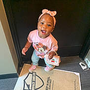 Sarah is registered to the contest to win money with this photo: toddler, child, girl, pink_headband, minnie_mouse_shirt, purse, smiling, standing, doorway, floor_mat, carpet, indoors, cute, happy, clothing, footwear, accessory, person, portrait, looking_up