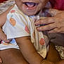 baby, smiling, infant, child, onesie, fruit_pattern, hand, pillow, happy, cute, sitting, indoors, person, skin, face, mouth_open, toes, support, closeup, joyful