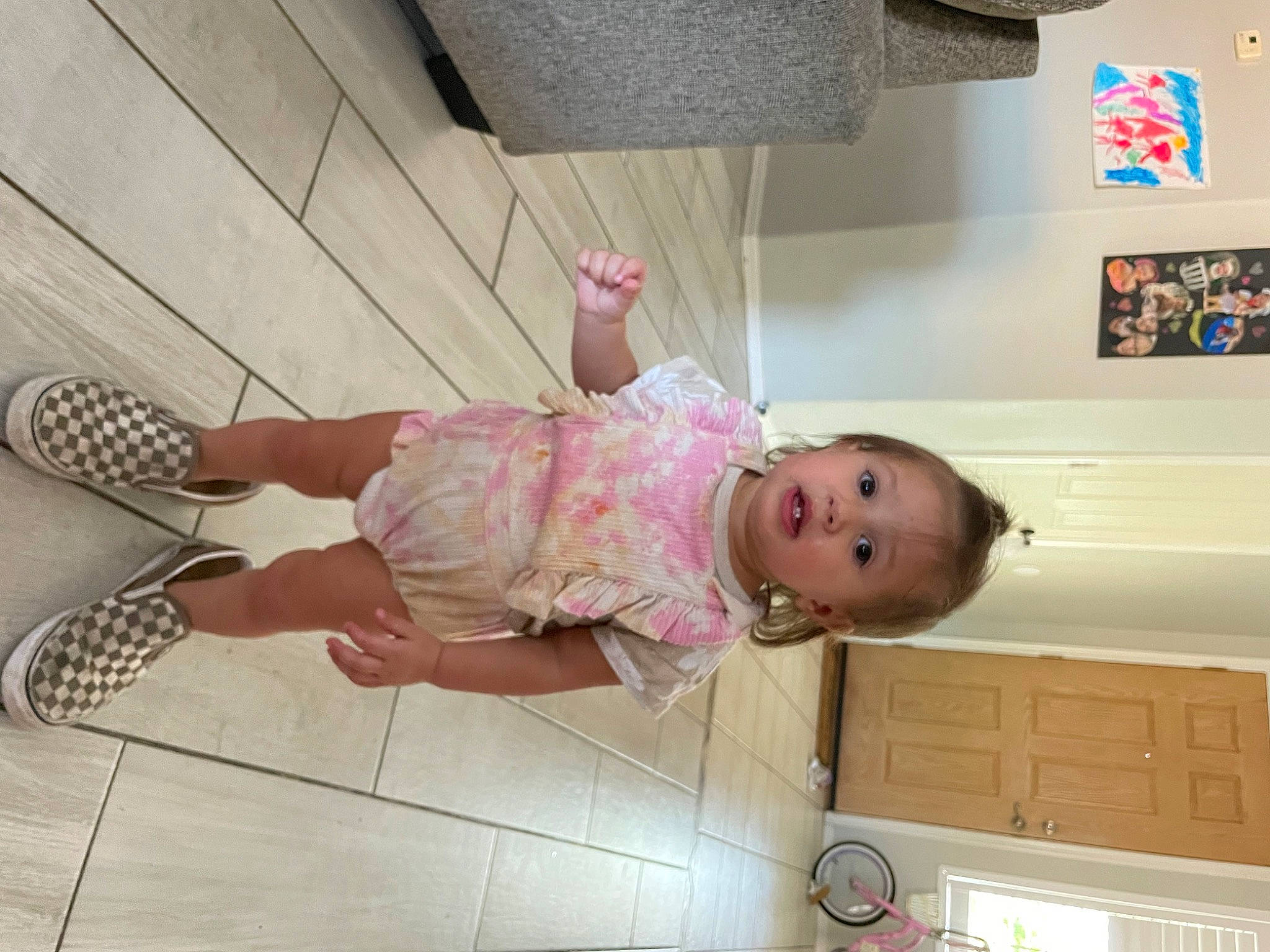 Oaklee is registered to the contest to win money with this photo: baby, baby_toddler_clothing, child, flooring, foot, fun, happy, human_leg, leg, mechanical_fan, person, room, sandal, smile, thigh, toddler, walking_shoe