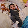 ai_generated, baby, baby_clothing, bed, bedding, blanket, child, dark_hair, face, indoors, infant, lying_down, nursery, pillow, plush_toy, portrait, socks, star_light, stuffed_toy, wide_eyes