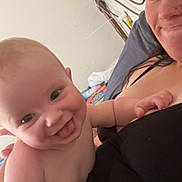Abraham is registered to the contest to win money with this photo: baby, child, woman, smiling, tongue_out, indoor, bed, blanket, person, face, skin, hair, happy, holding, casual_clothing, furniture, head, comfort, cozy, portrait
