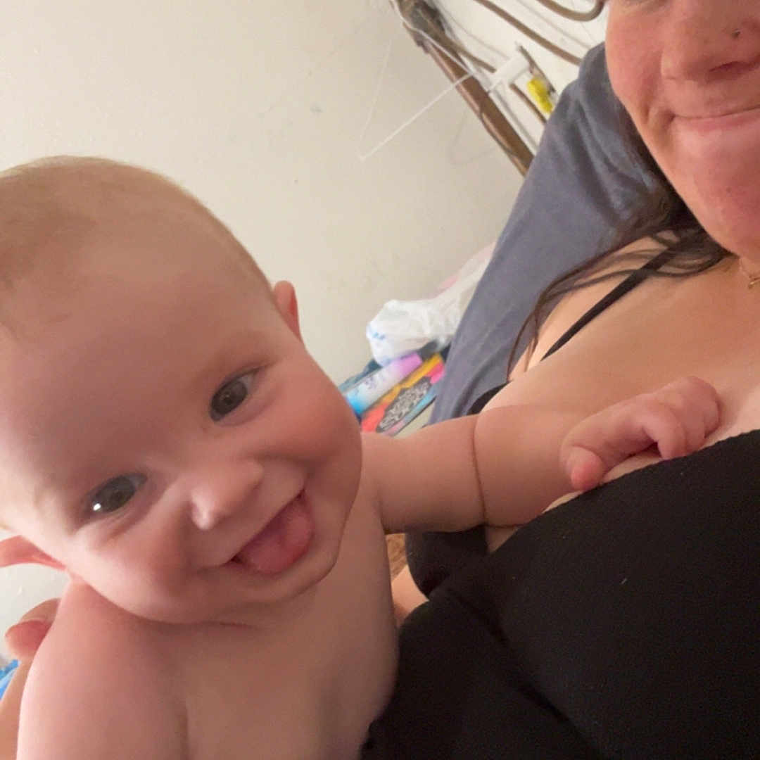 Abraham is registered to the contest to win money with this photo: baby, bed, blanket, casual_clothing, child, comfort, cozy, face, furniture, hair, happy, head, holding, indoor, person, portrait, skin, smiling, tongue_out, woman