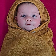Luc participe au concours pour gagner de l'argent avec cette photo : baby, towel, hood, face, blue_eyes, skin, blanket, infant, child, portrait, expression, closeup, cute, warm, soft_texture, pink_background, wrapped, lying_down, indoors, person