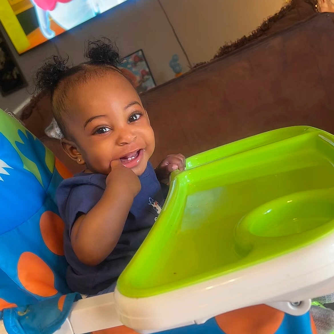Marquell is registered to the contest to win money with this photo: baby, cartoon, child, christmas_tree, cute, earrings, feeding, furniture, hair_buns, happy, high_chair, infant, living_room, playful, polka_dot, portrait, smile, television, toy, tray