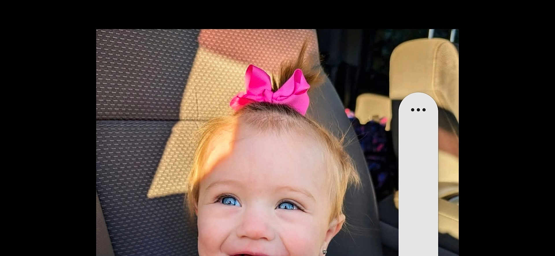 Morti is registered to the contest to win money with this photo: baby, blue_eyes, car_seat, cheeks, child, close_up, eyelashes, hair_bow, happy, head, passenger, pink_bow, playful, portrait, seat, shadow, smile, sunlight, toddler, vehicle_interior