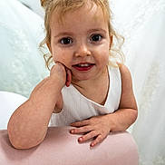 Yosemite joined the competition — help win amazing prizes! child, toddler, girl, portrait, closeup, smile, hair_buns, white_dress, pink_couch, hands, arm, indoors, big_eyes, baby_teeth, curly_hair, playful, innocence, candid, furniture, young