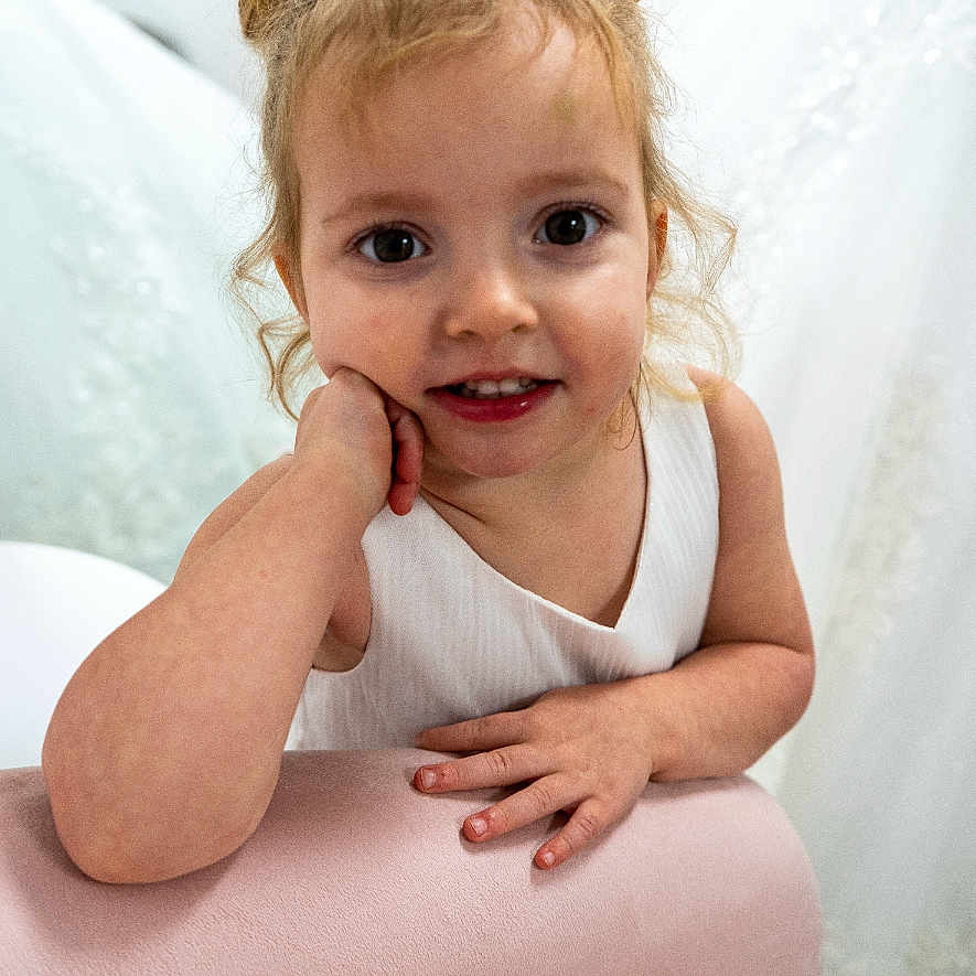 Yosemite joined the competition — help win amazing prizes! arm, baby_teeth, big_eyes, candid, child, closeup, curly_hair, furniture, girl, hair_buns, hands, indoors, innocence, pink_couch, playful, portrait, smile, toddler, white_dress, young