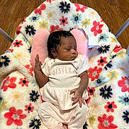 Cali is registered to the contest to win money with this photo: newborn, baby, infant, sleeping, portrait, child, face, hand, onesie, little_sister, pink, blanket, floral, flowers, play_mat, indoor, wood_floor, chair, relaxed, adorable