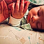 baby, sleeping, hand, pillow, pattern, arrows, love, dance, closeup, infant, peaceful, resting, soft_focus, skin, clothing, toddler, adult_hand, nap, cute, warm_lighting
