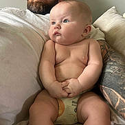 Mary is registered to the contest to win money with this photo: arm, baby, beard, blue_eyes, casual, child, closeup, couch, diaper, family, hand, indoor, man, person, pillow, portrait, relaxed, sitting, skin, tattoo