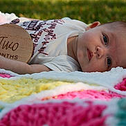 Rayne joined the competition — help win amazing prizes! baby, infant, blanket, crochet, outdoor, grass, wooden_plaque, two_months, clothing, person, face, head, skin, hand, lying_down, colorful, soft_texture, young_child, cute, portrait