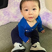 Emmett joined the competition — help win amazing prizes! baby, child, blue_clothing, sneakers, white_shoes, carpet, plush_cushion, indoor, floor, sitting, portrait, curious, young_child, casual_wear, smiling, cute, small_hands, head, face, eyes