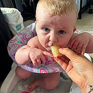 Ariella joined the competition — help win amazing prizes! baby, blond_hair, blue_eyes, bracelet, child, colorful, cute, eating, face, food, hand, highchair, indoor, infant, person, playmat, rainbow, seat, small_hand, toy