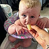 baby, blond_hair, blue_eyes, bracelet, child, colorful, cute, eating, face, food, hand, highchair, indoor, infant, person, playmat, rainbow, seat, small_hand, toy