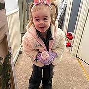 Layana is registered to the contest to win money with this photo: toddler, child, indoor, carpet, jacket, gloves, crown, pink, bottle, shoes, footwear, person, smiling, happy, christmas_tree, holiday, toy, clothing, door, floor