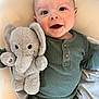 Hudson is registered to the contest to win money with this photo: baby, smiling, plush_toy, elephant, green_pajamas, infant, cute, child, face, happy, soft_toy, indoors, cozy, portrait, young_child, sitting, blanket, cuddly, playful, cute_expression