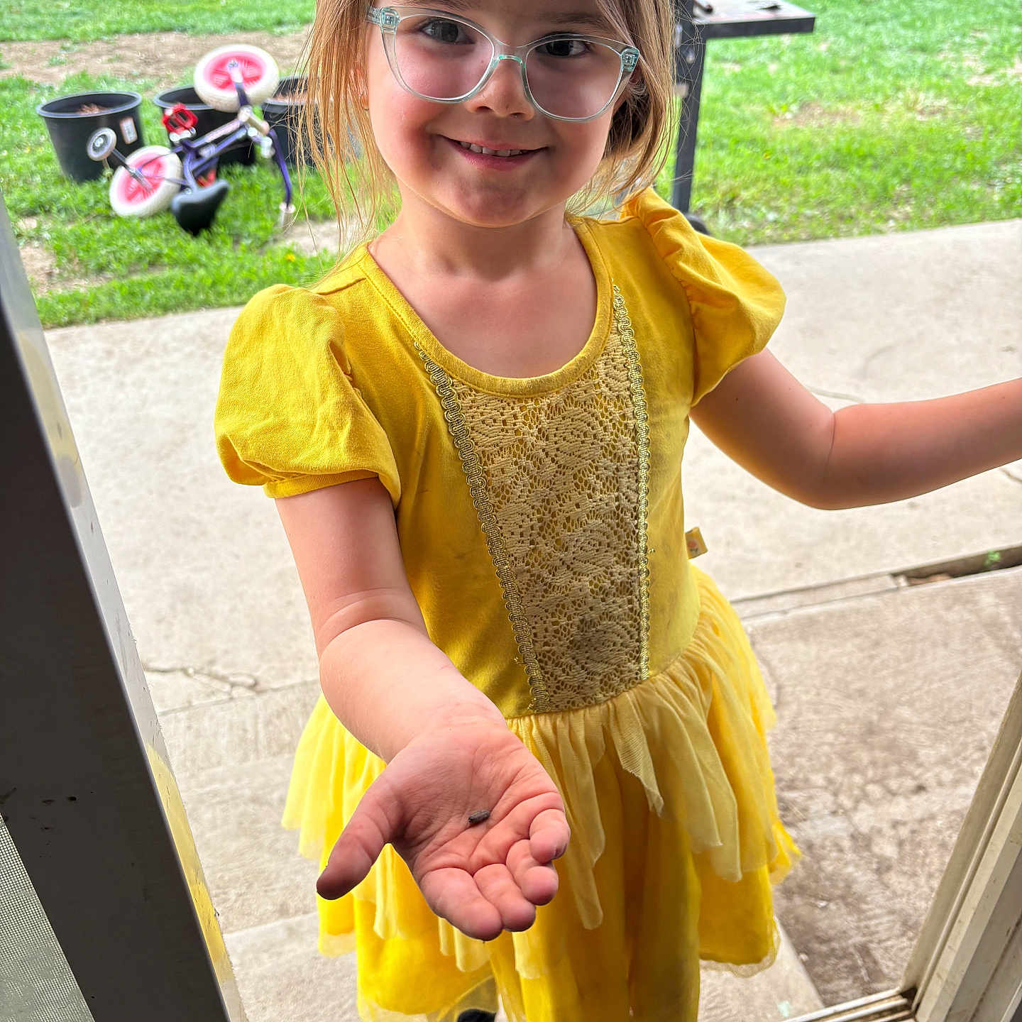 Kynsley is registered to the contest to win money with this photo: backyard, bicycle, casual_clothing, child, concrete, doorway, footwear, garden_beds, girl, glasses, grass, hand, happy, outdoor, person, playground_equipment, short_hair, smiling, summer, yellow_dress