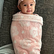 Selena is registered to the contest to win money with this photo: baby, blanket, pink, bow, headband, face, smile, couch, fabric, pattern, child, cute, infant, wrapped, portrait, soft, indoor, happy, eyes, person