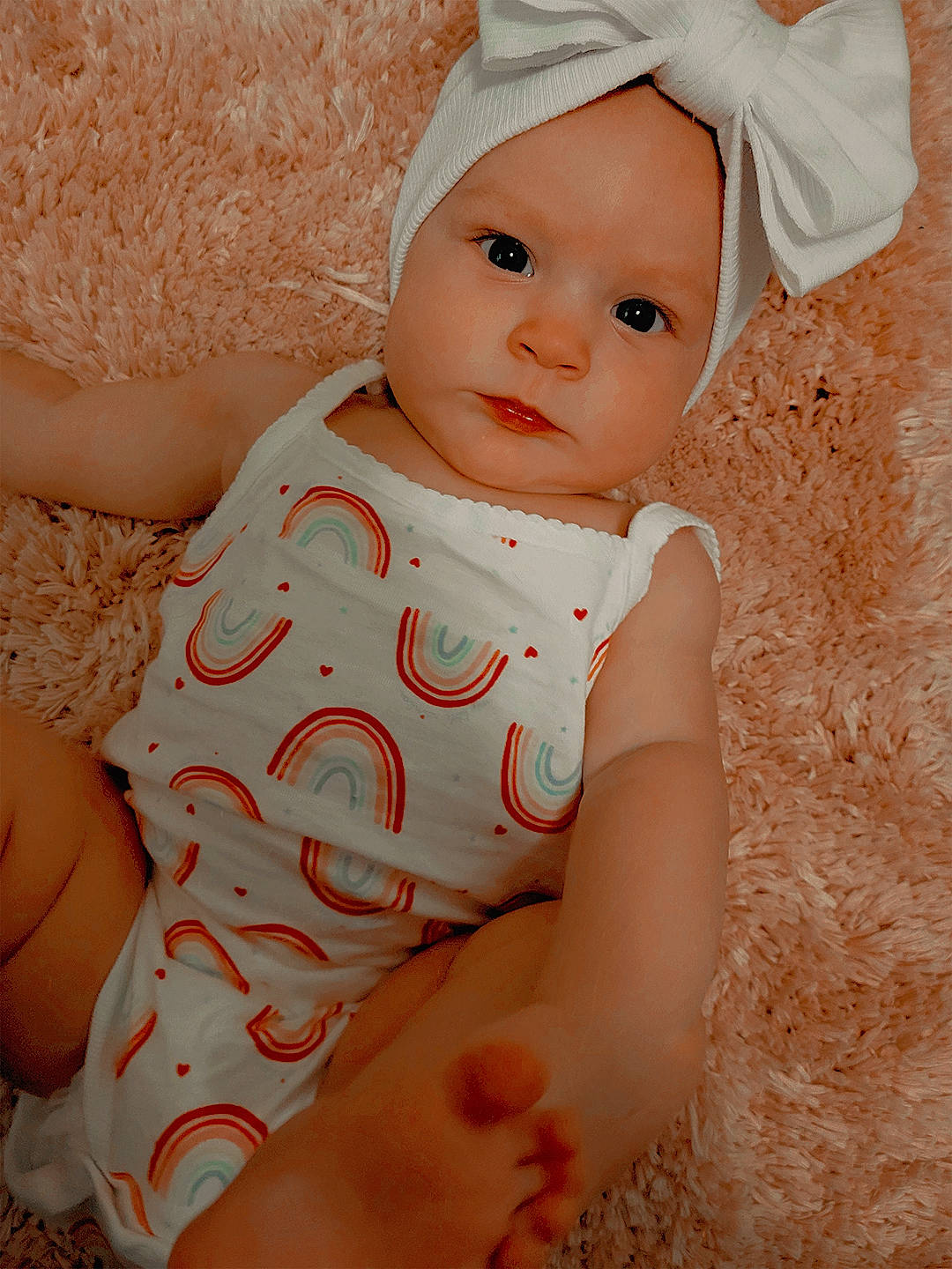Wynona is registered to the contest to win money with this photo: baby, baby_toddler_clothing, cap, cheek, child, comfort, elbow, fashion_accessory, finger, happy, headwear, human_body, human_leg, lip, pattern, person, pink, sitting, skin, sleeve