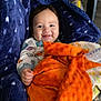 baby, blanket, blue_blanket, orange_blanket, baby_seat, pajamas, smiling, infant, indoor, toy, gnome, face, hand, cozy, floor, carpet, child, comfort, cute, portrait