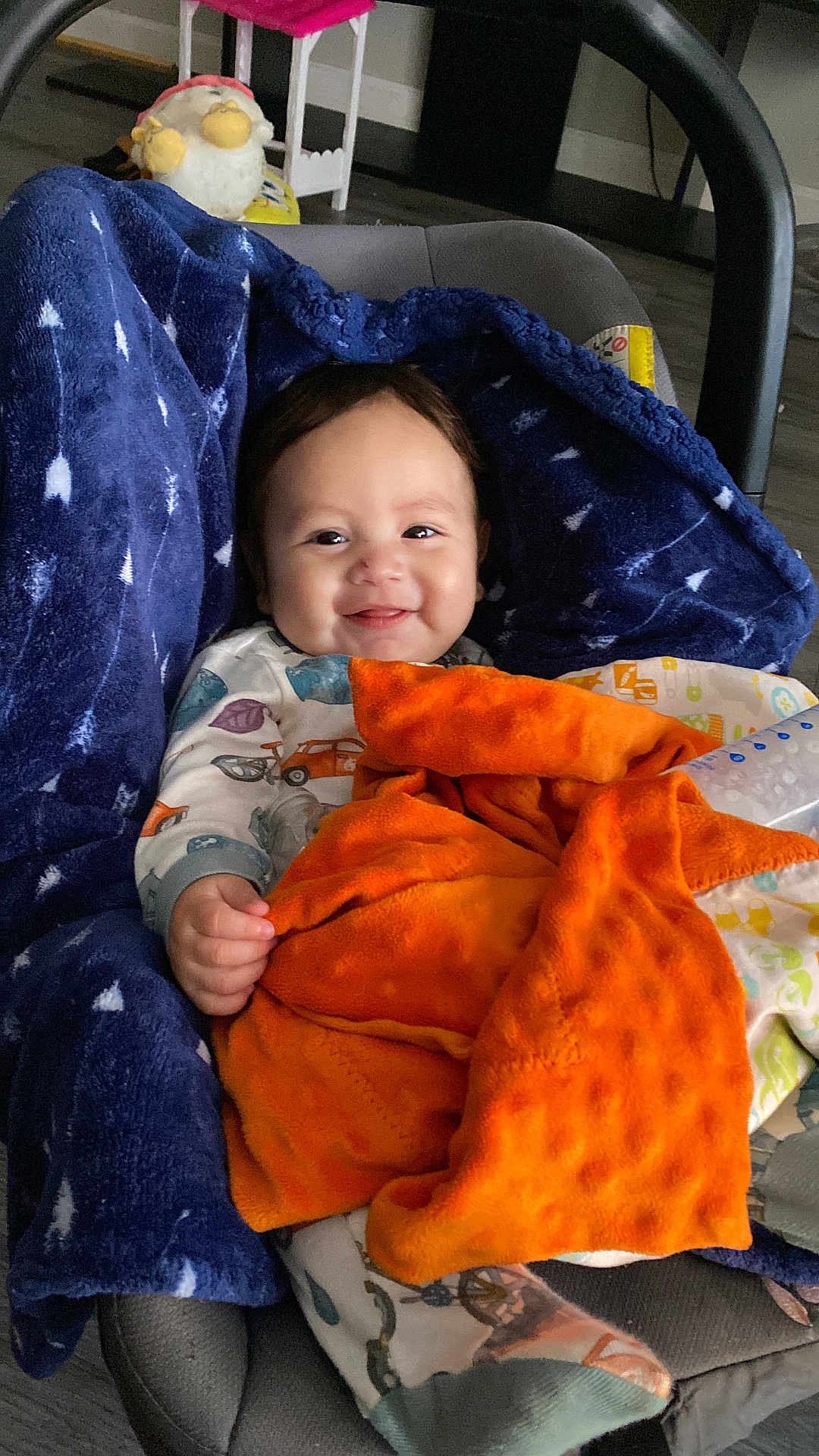 Tristan joined the competition — help win amazing prizes! baby, blanket, blue_blanket, orange_blanket, baby_seat, pajamas, smiling, infant, indoor, toy, gnome, face, hand, cozy, floor, carpet, child, comfort, cute, portrait