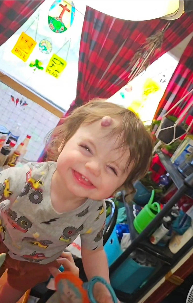 Cain is registered to the contest to win money with this photo: baby, cheek, child, city, event, fun, green, happy, head, joy, kindergarten, leisure, pattern, person, plaid, play, recreation, room, smile, t_shirt