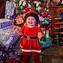 Ayaru joined the competition — help win amazing prizes! baby, christmas_tree, presents, holiday, festive, red_dress, smiling, indoors, decorations, ornaments, santa_hat, child, happy, lights, gift_wrap, floor, carpet, toy, furniture, celebration