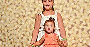 Savannah joined the competition — help win amazing prizes! child, children, smiling, portrait, dress, holding_hands, bokeh_background, happy, girl, young_child, sleeveless_dress, standing, curly_hair, bracelet, wristband, studio_photo, cute, innocence, family, together