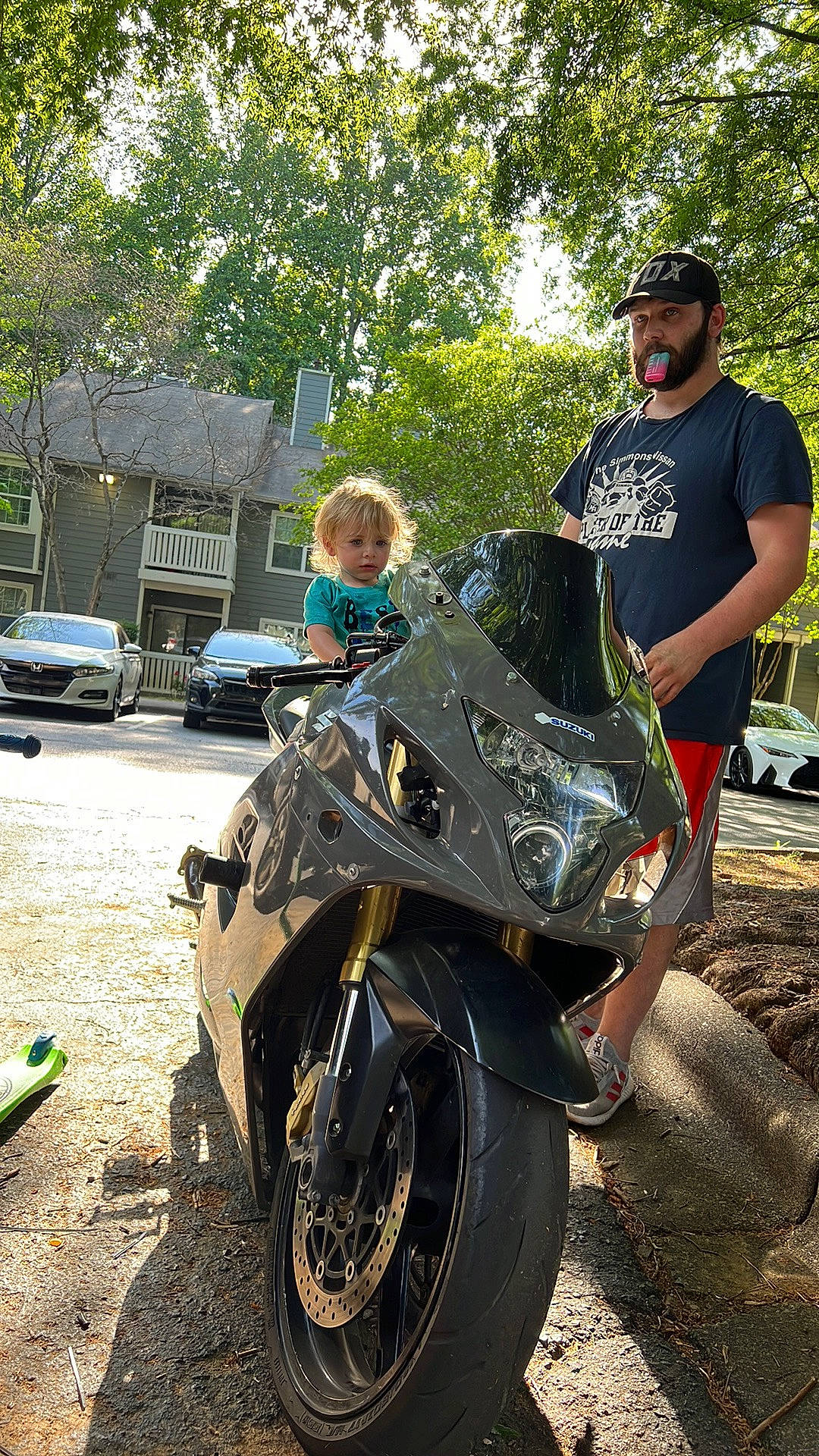 Donavan is registered to the contest to win money with this photo: alloy_wheel, asphalt, automotive_design, automotive_exterior, automotive_lighting, automotive_tire, car, fuel_tank, hat, headlamp, headwear, motor_vehicle, motorcycling, person, plant, rim, rolling, tire, tread, tree