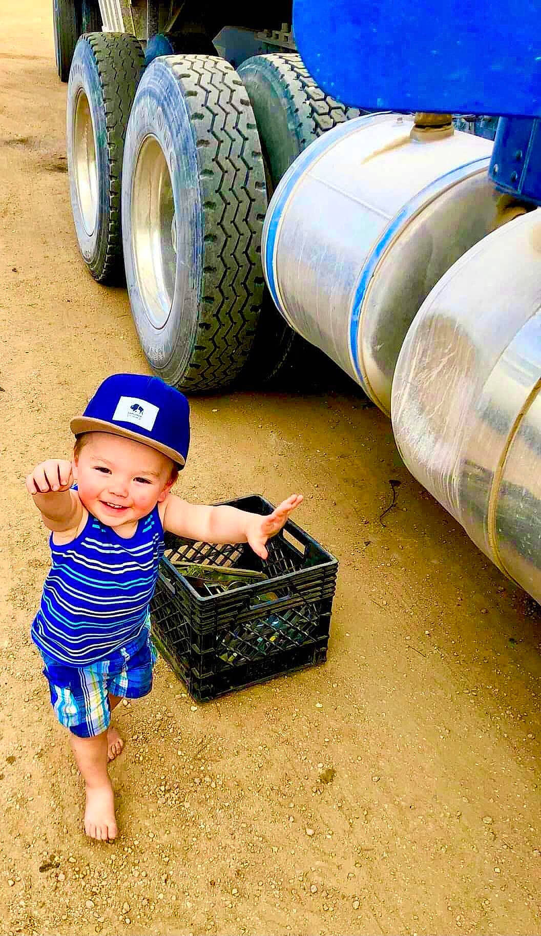 Terrell Jr is registered to the contest to win money with this photo: automotive_tire, automotive_wheel_system, blue, cap, electric_blue, grass, green, hat, headgear, headwear, jeans, joy, motor_vehicle, person, smile, sun_hat, sunglasses, synthetic_rubber, tire, toddler
