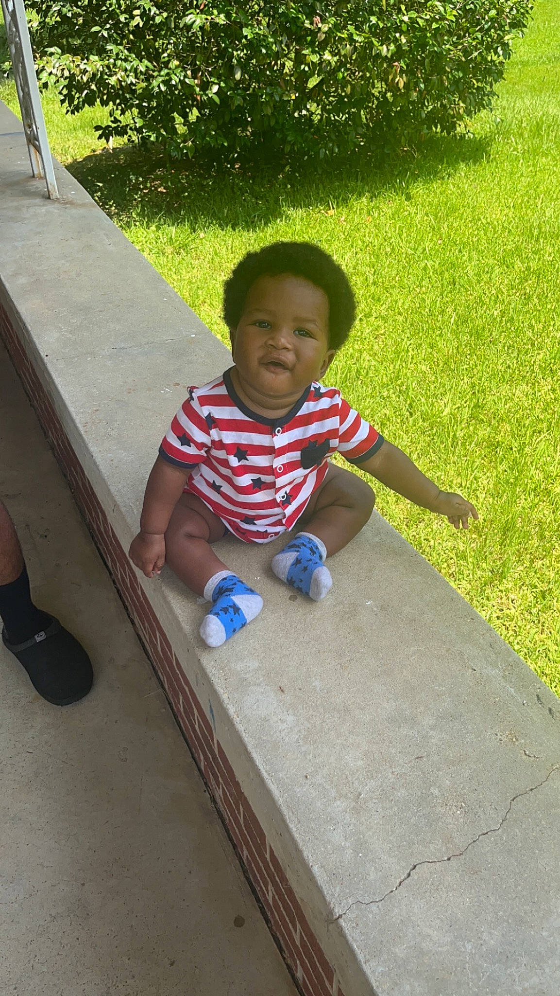 Josiah joined the competition — help win amazing prizes! baby, baby_toddler_clothing, concrete, facial_expression, flooring, fun, grass, leaf, leisure, person, plant, recreation, road_surface, sidewalk, sitting, smile, sneakers, t_shirt, toddler, tree