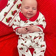 Gerard is registered to the contest to win money with this photo: baby, infant, smiling, pajamas, red, white, blanket, christmas, holiday, pattern, clothing, cute, child, face, hands, lying_down, cozy, happy, indoors, portrait
