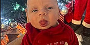 Gerard is registered to the contest to win money with this photo: baby, child, christmas_tree, ornaments, holiday, festive, red_clothing, reindeer, tongue_out, cute, indoor, person, celebration, smile, christmas_decorations, toy, holiday_lights, seasonal, festivity, infant