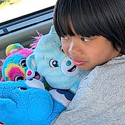 Ivan is registered to the contest to win money with this photo: child, plush_toys, bear, car_interior, window, daylight, toy, cuddling, colorful, soft, hair, face, clothing, seat, cute, portrait, person, happy, childhood, indoors