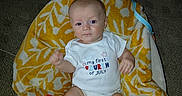 Nehemiah joined the competition — help win amazing prizes! baby, infant, onesie, socks, blanket, patterned_blanket, carpet, indoor, baby_seat, red, white, yellow, cute, child, portrait, clothing, footwear, celebration, holiday, expression
