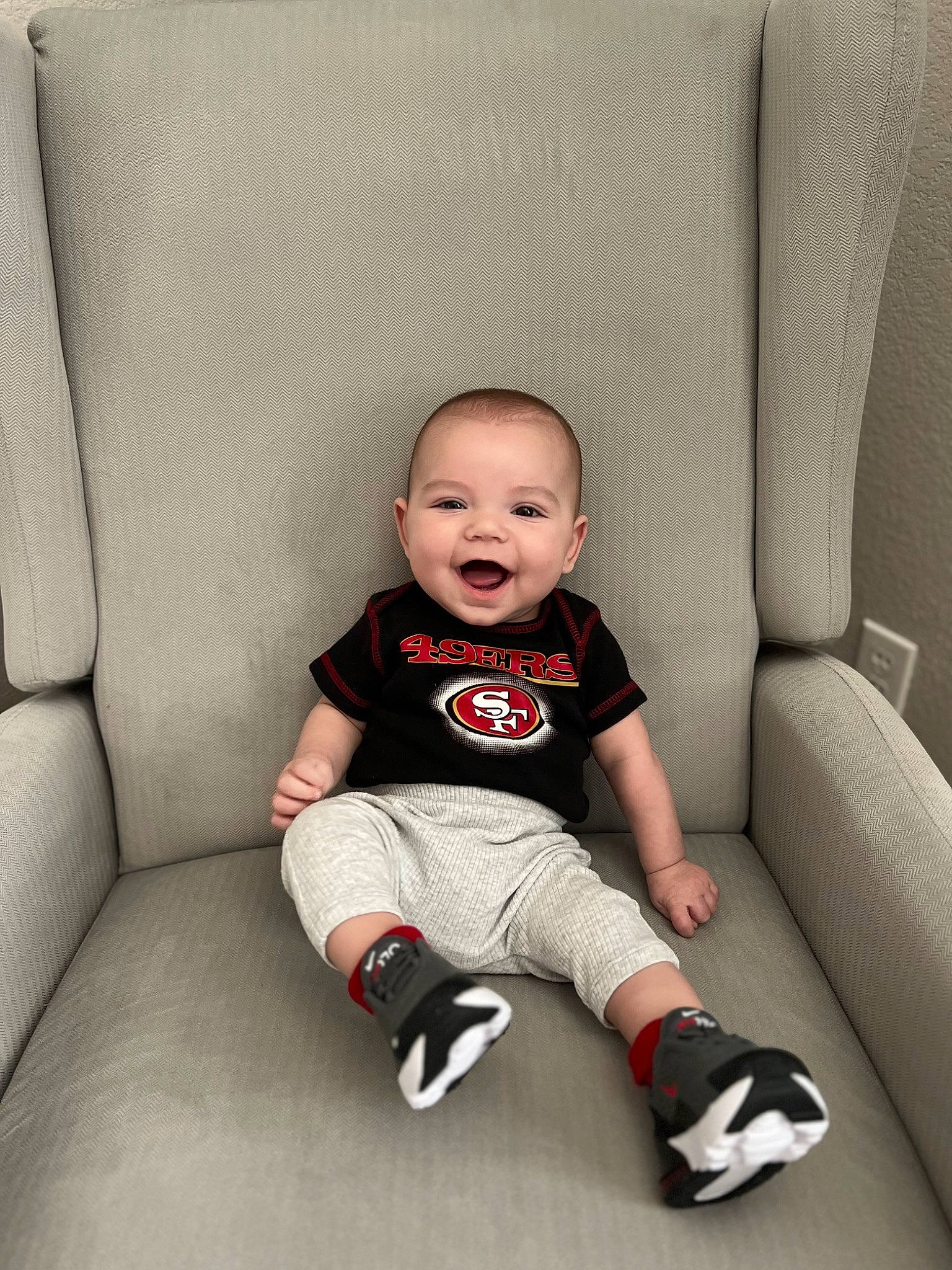 Austin is registered to the contest to win money with this photo: baby, baby_toddler_clothing, carmine, chair, child, comfort, couch, flash_photography, flooring, happy, knee, person, portrait_photography, rectangle, room, sitting, sleeve, smile, t_shirt, toddler