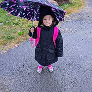 Bexley joined the competition — help win amazing prizes! backpack, black, child, curious, footwear, grass, hood, outdoor, pavement, person, pink, rain, raincoat, road, rock, shoes, standing, umbrella, weather, wet