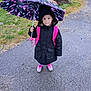 backpack, black, child, curious, footwear, grass, hood, outdoor, pavement, person, pink, rain, raincoat, road, rock, shoes, standing, umbrella, weather, wet