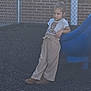 Bexley joined the competition — help win amazing prizes! beige_pants, boots, brick_wall, casual_pose, child, clothing, daylight, expression, fence, leisure, outdoor, person, play_area, playground, slide, standing, toddler, top_bun, white_shirt, young_girl