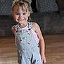 casual_clothing, child, couch, cute, girl, hair_tied, happy, home, indoor, light, overalls, person, pillow, playful, portrait, smiling, standing, tank_top, wooden_floor, young