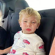 Waylon joined the competition — help win amazing prizes! toddler, child, blonde_hair, car_seat, seatbelt, white_shirt, firetruck_print, clothing, portrait, car_interior, window, seat, person, young_child, casual, sitting, daylight, expression, indoors, young_toddler