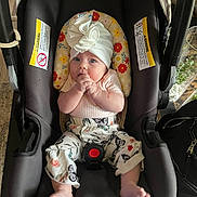 Maple joined the competition — help win amazing prizes! baby, infant, car_seat, white_hat, floral_pants, hands, feet, face, child, indoors, sitting, looking, curious, colorful, patterned, clothing, seatbelt, safety, cute, portrait