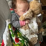 baby, child, sleeping, stuffed_animal, blanket, cactus_pattern, striped_clothing, indoor, cozy, naptime, soft_toy, infant, cute, resting, peaceful, curly_hair, hand, seat, plush, comfort