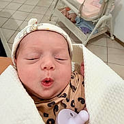 Alys is registered to the contest to win money with this photo: baby, newborn, infant, swaddle, hat, pacifier, bassinet, blanket, tile_floor, onesie, cute, mouth_open, facial_expression, nursery, crib, indoor, home, parent_hand, sleepy, baby_clothing