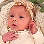 baby, newborn, infant, headband, bow, knit_blanket, cream_outfit, hand, face, eyes_open, portrait, close_up, soft_lighting, skin, nursery_prop, eucalyptus, basket, adorable, sleepy, peaceful