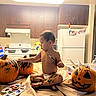 child, toddler, baby, diaper, sitting, painting, paintbrush, pumpkin, jack_o_lantern, halloween, kitchen, indoor, refrigerator, stove, sink, countertop, art_supplies, palette, creative, portrait