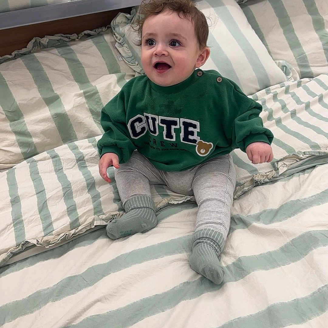 Manasseh is registered to the contest to win money with this photo: baby, bed, bedroom, clothing, cushion, face, furniture, happy, head, homedecor, hosiery, indoors, laughing, pants, person, photography, portrait, room, sitting, sock