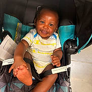 Khai joined the competition — help win amazing prizes! baby, carriage, child, clothing, eyes, face, feet, hands, happy, indoor, infant, onesie, photography, portrait, safety_harness, sitting, smiling, stroller, teal, tile_floor